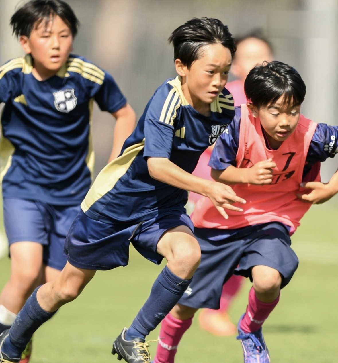 相手と競り合いながら走るWISDOMの選手と、近くで支える味方